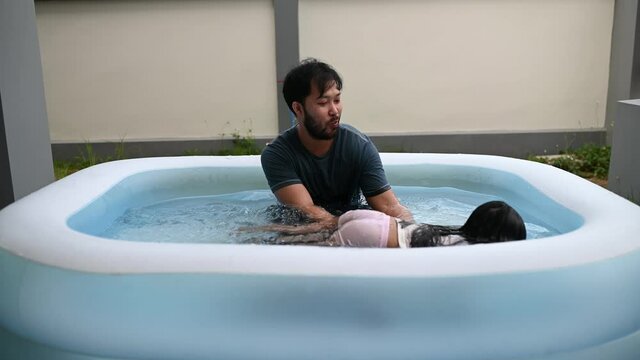 Father day concept,Asian dad and daughter use time together at home,Play in the inflatable pool