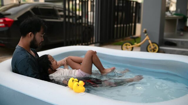 Father day concept,Asian dad and daughter use time together at home,Play in the inflatable pool