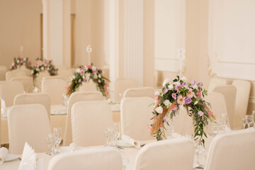 Centerpiece made of green leaves and fresh flowers stands on the dinner table. Wedding day. Fresh flowers decorations.