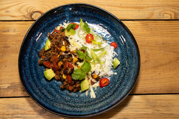 A delicious plate of a Burrito fillings with salad on a wooden kitchen restaurant table