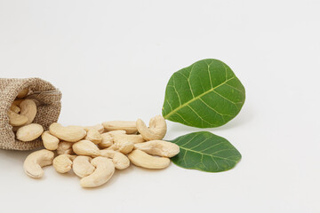 Cashew nuts with green leaf in bag isolated on white background