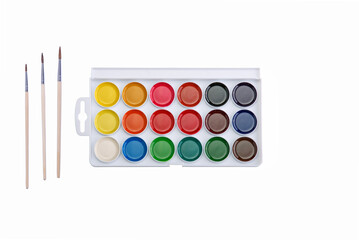 Multicolored aquarelle paints in paint box with brushes on white background.