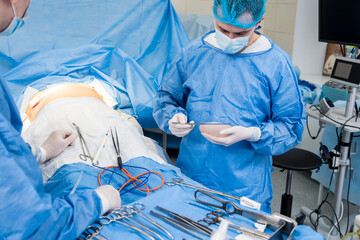 Breast augmentation under the guidance surgeons team in surgical operating room.