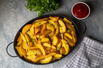 Roasted potato wedges with herbs and sea salt on plate, top view (Turkish name; elma dilim patates)