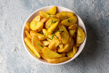 Roasted potato wedges with herbs and sea salt on plate, top view (Turkish name; elma dilim patates)