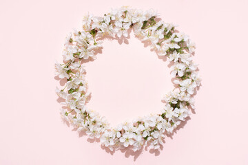 Round frame, wreath of white cherry flowers on a pink background, spring, wedding background.