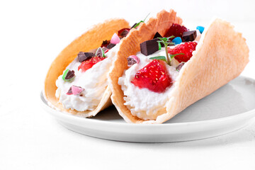 Sweet tacos with thin waffle, cottage cheese cream and strawberry topped with chocolate and mint. Dessert variation of Mexican classics