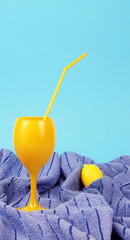 Yellow cocktail glass summer drink beverage lemon juice with yellow straw on blue towel beach concept minimal aesthetic