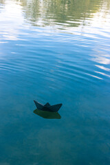 Black paper boat floats on the river