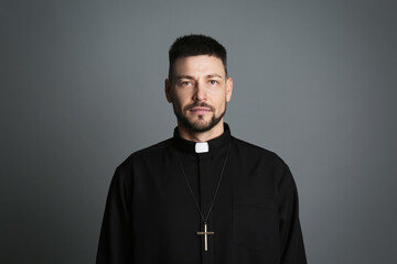 Obraz premium Priest wearing cassock with clerical collar on grey background