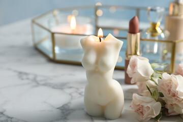 Beautiful female body shaped candle on white marble table. Space for text
