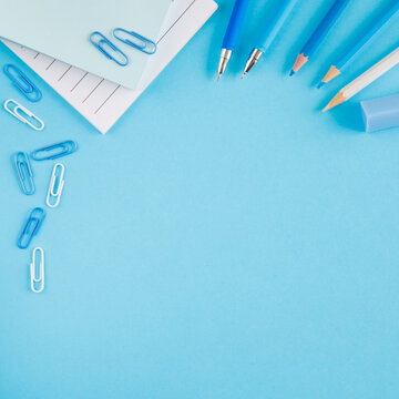 Frame of white and blue school supplies on an bright blue background. Concept back to school. School or stationery shop spring summer sea concept. Copy space, flat lay, top view, background.