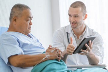 happy asian elderly looking at a good result of health check up in the medical chart with doctor.