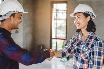 Successful deal, male architect shaking hands with client in construction site after confirm blueprint for renovate building.