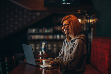 Busy redhead woman working on her laptop in a cafe