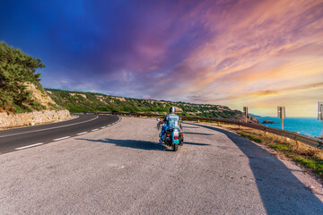 Obraz premium Biker on a winding road under a pink sky