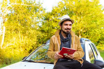 Latino farmer sitting on his off-road car using modern technologies to do his work in the field at sunset. Hispanic man using digital tablet on his farm.