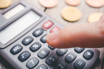 Finger Touching A Calculator With Coins In Background - Accounting Concept