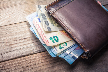 Euro Banknotes Showing Out Of A Brown Leather Wallet On A Wooden Board Viewing From Above
