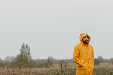 A bearded man in a raincoat on the background of nature. Background for the poster.