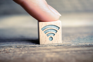 WIFI Icon On A Wooden Block On A Board Touched By A Finger