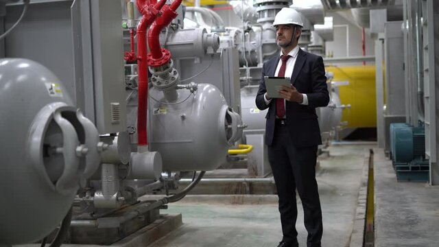 Industry Engineer manager using digital tablet checking information and safety system of the machine in boiler room at Industrial Manufacturing Factory. businessman inspecting machinery in plant