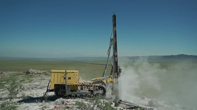 In a mountainous area, a drilling rig makes a hole in a rocky rock, preparing a section of rock for blasting.