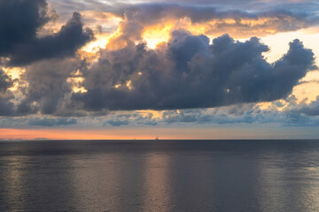 a small boat on the horizon at sunrise with incredible clouds