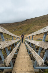 Man walking looking at his phone on wooden bridge