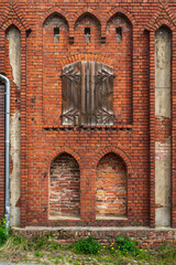 Old brick wall with windows and a door in the Gothic style.