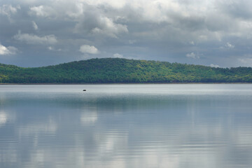 boat with passengers in distance under heavy colds in a calm lake