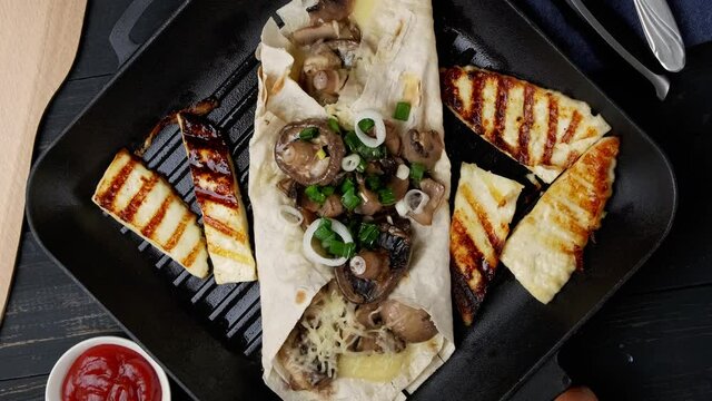 Assortment of street food on a dark wood table. mushrooms, shawarma, Adyghe cheese, herbs, noodles. Served on fried bread. Top view