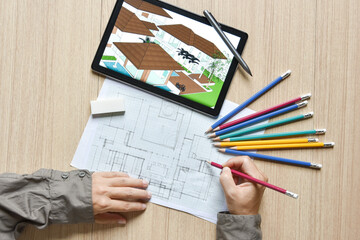 a tablet showing architectural drawing design detail building perspective and draft plan with digital pens on wood table, the concept of new technology for working of tablet with digital pen