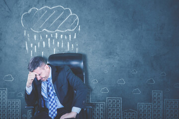 Depressed caucasian businessman sits under raining