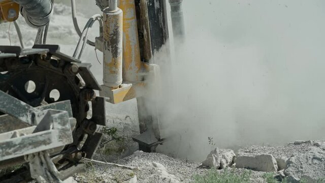 Slow-motion close-up, In a mountainous area, a drilling rig makes a hole in the rock, preparing a section of rock for blasting.