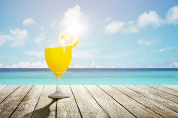 Fresh orange juice with a straw on tropical beach