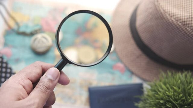 young man using magnifying glass looking something on map 