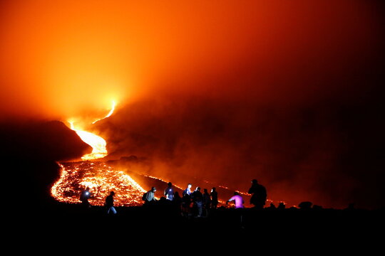 People watch as streams of red hot lava flow during an eruption of the Pacaya volcano at San Vicente de Sales municipality in the Escuintla region