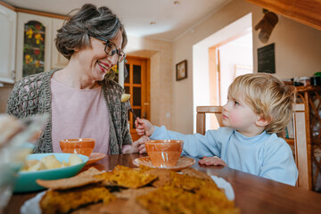 Grandson treat grandmother with cookies at the kitchen.