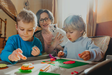 Grandmother playing with her grandchildren with kids play clay
