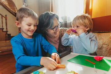 Grandmother playing with her grandchildren with kids play clay