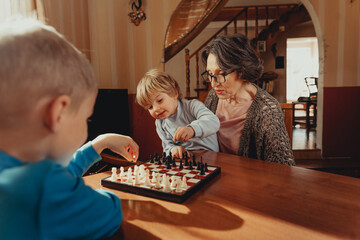 Two brothers learning play chess in the room