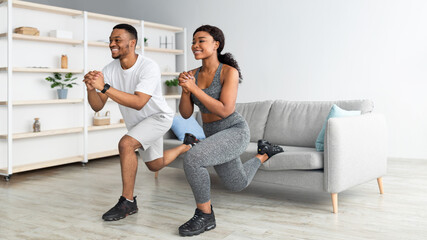 Athletic black couple doing lunges on home workout, copy space. Domestic training during covid...