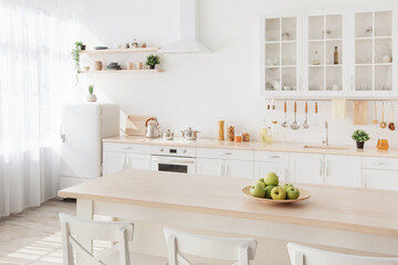 Fototapeta na wymiar Bright kitchen interior. White furniture and shelves with utensils and plates, small refrigerator near window