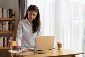 Young Asian businesswoman working at her house with laptop, working at home, business concept