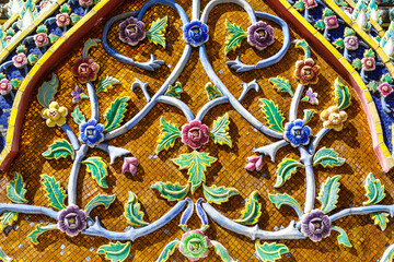 Beautiful pediment of a Buddhist temple decorated with ceramic mosaics depicting flowers