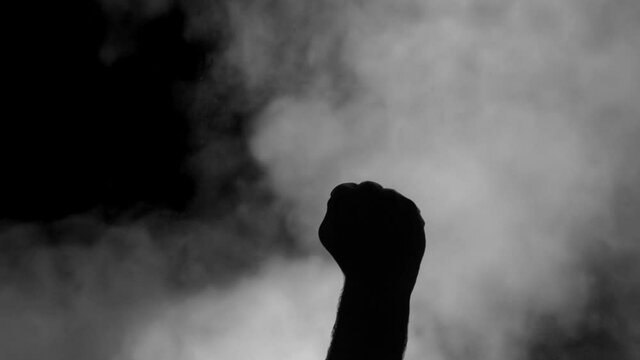 A male hand (silhouetted over a dark gray background of rising smoke), making a rude vulgar gesture with his middle finger. Multiple takes.
