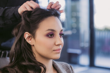 Young woman getting hair styling and makeup in a beauty salon.