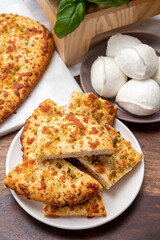 Tasty italian vegetarian food, fresh baked flat foccachia bread with white mozzarella cheese and herbs