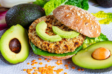 Tasty vegetarian healthy food, homemade burgers made from orange lentils legumes with green lettuce and fresh ripe avocado